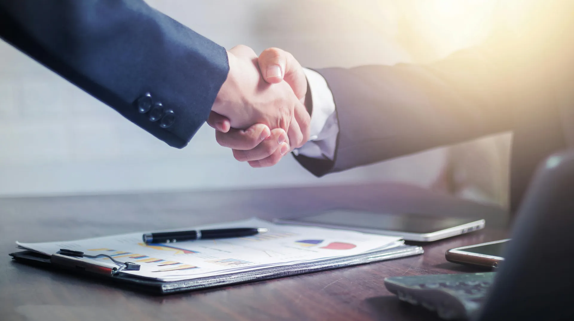 Business handshake over financial charts